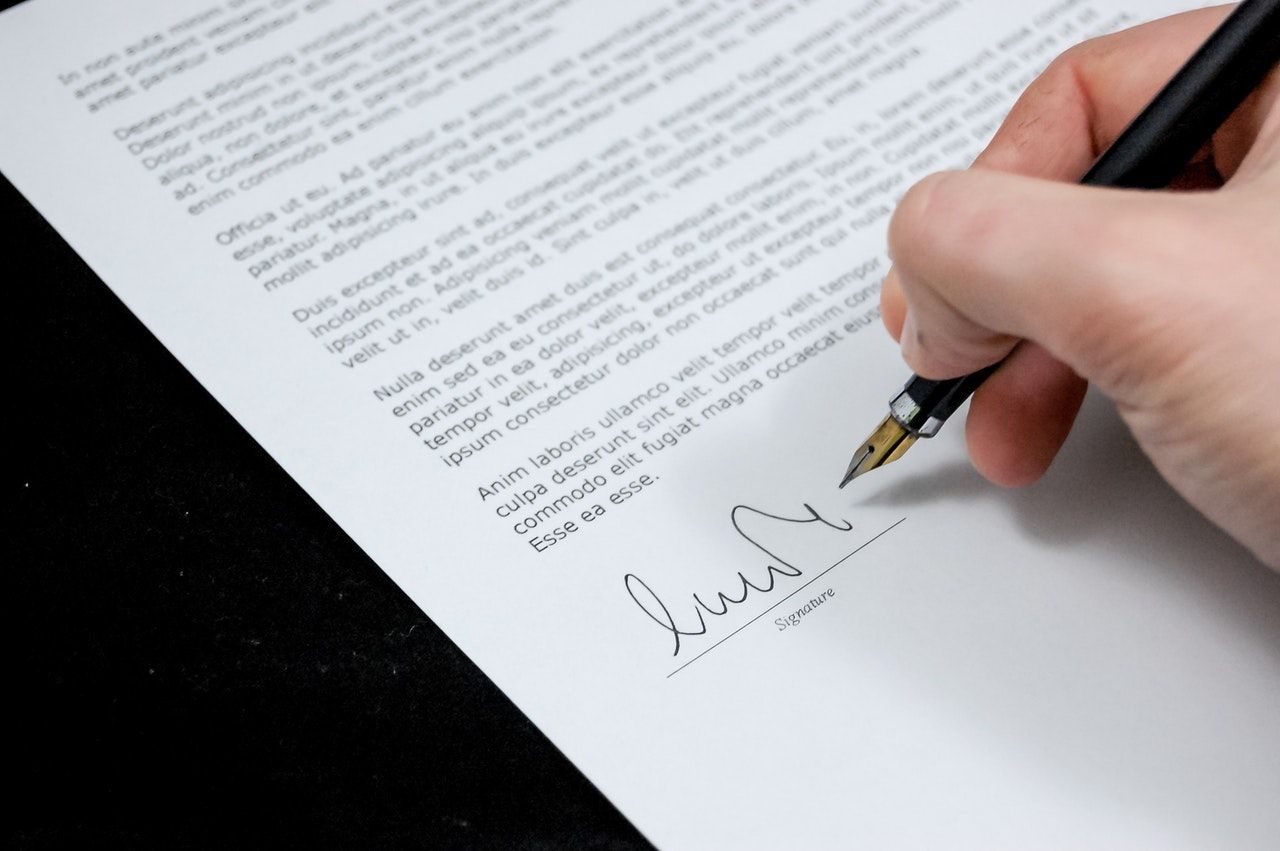 man signing paper with a pen